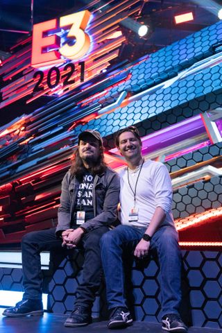 two men sitting under E3 2021 sign 