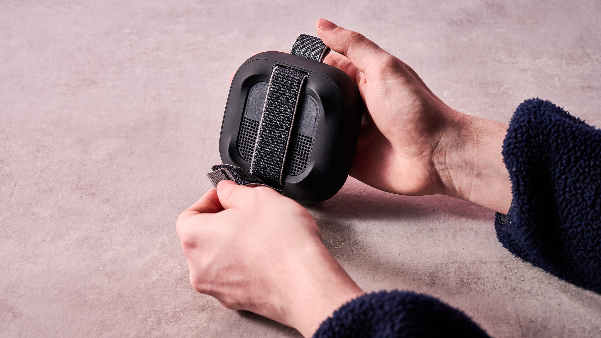 Man adjusting strap on the reverse side of the Bose SoundLink Micro Gen 2