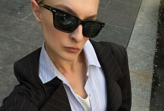 Christie Tyler in black sunglasses, a blazer, and a button down shirt.