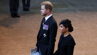 Prince Harry and Meghan, Duchess of Sussex walk as procession with the coffin of Britain's Queen Elizabeth arrives at Westminster Hall from Buckingham Palace for her lying in state on September 14, 2022