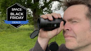 A man looking through a Bushnell Legend 10x42 monocular with grass and trees in the background with a black Space.com Black Friday deals badge in the upper left corner.