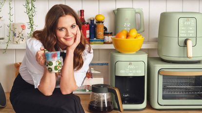 Drew Barrymore sitting on kitchen counter beside her Beautiful collection of kitchen appliances