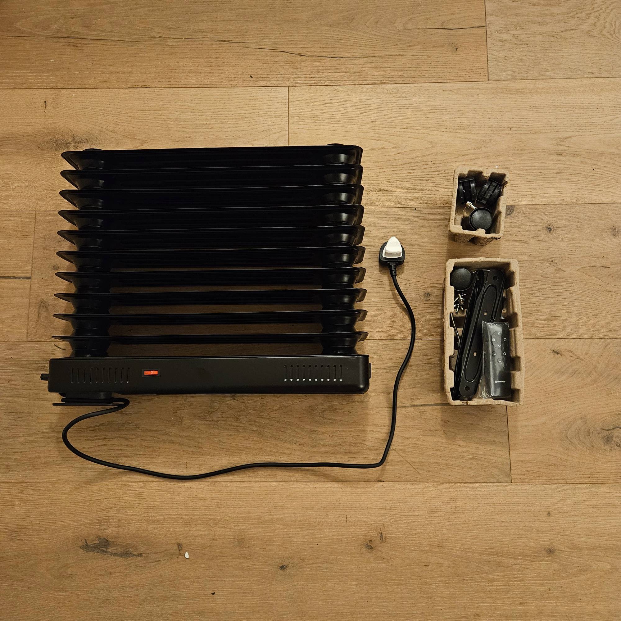 black oil filled radiator on floor before assembly