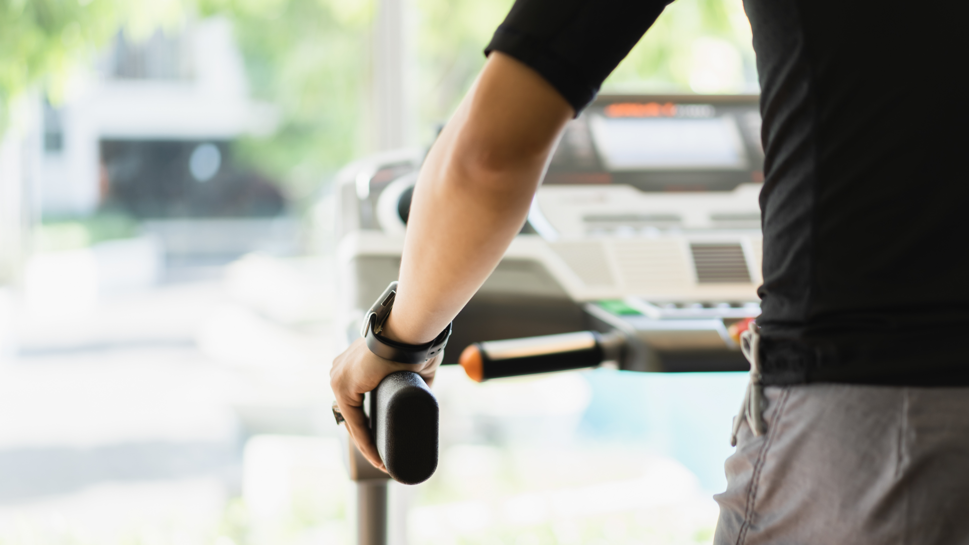 A man walking on a treadmill and holding onto the handle bars