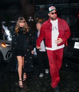 Taylor Swift in a long, crystal-embellished black coat and Travis Kelce, wearing red pants and a matching red jacket, while out in New York City on December 28, 2024