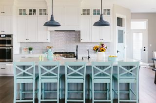 white kitchen with tiled splashback and statement light blue bar seating around the island