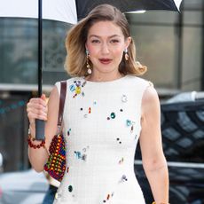 Gigi Hadid wearing a tweed dress with gem embellishments and a beaded bag