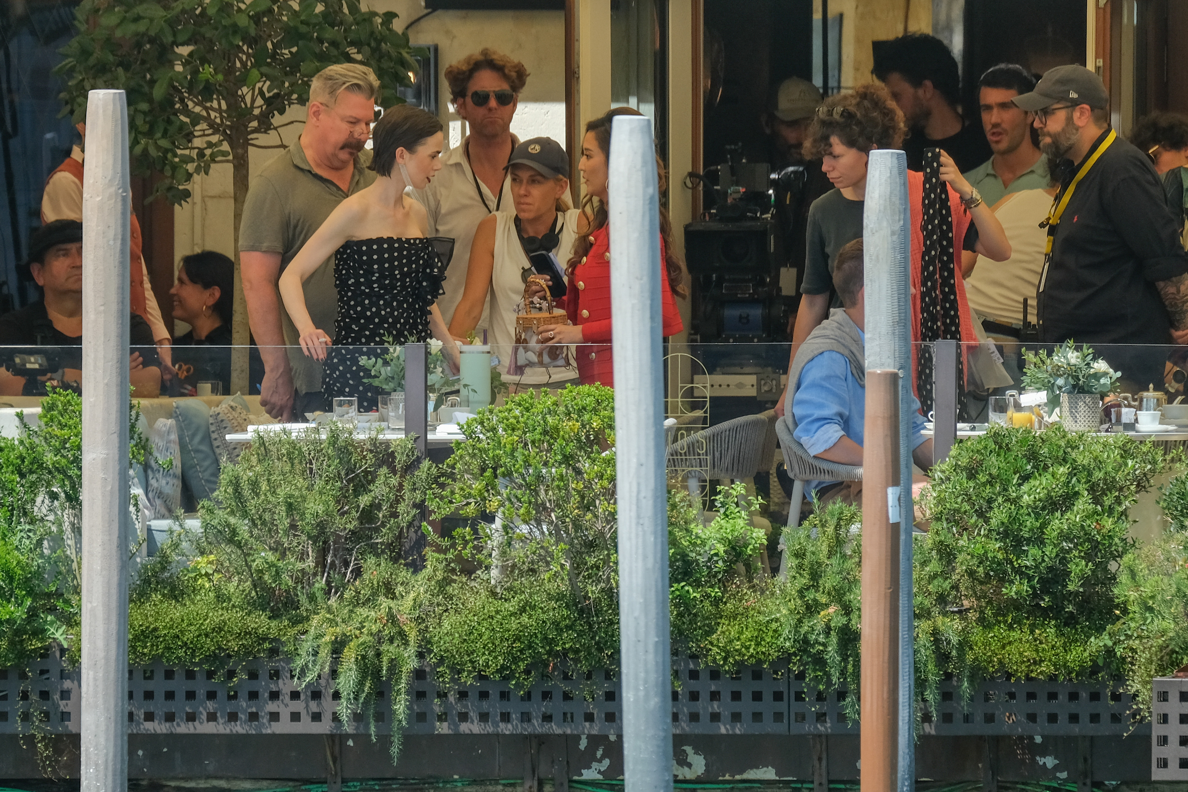 Lily Collins filming Emily in Paris wearing a navy and white polka-dot gown