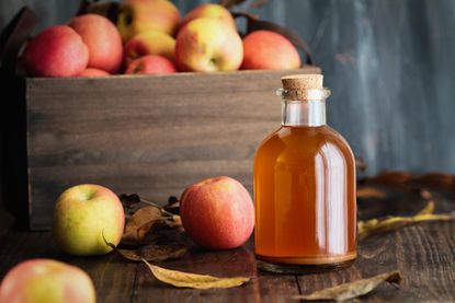 A bottle of apple cider vinegar and apples