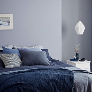 bedroom with blue wall and bed with blue cushions