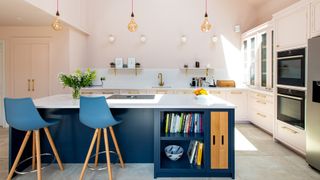 kitchen with pink walls and navy blue kitchen island with seating, storage and oven incorporated