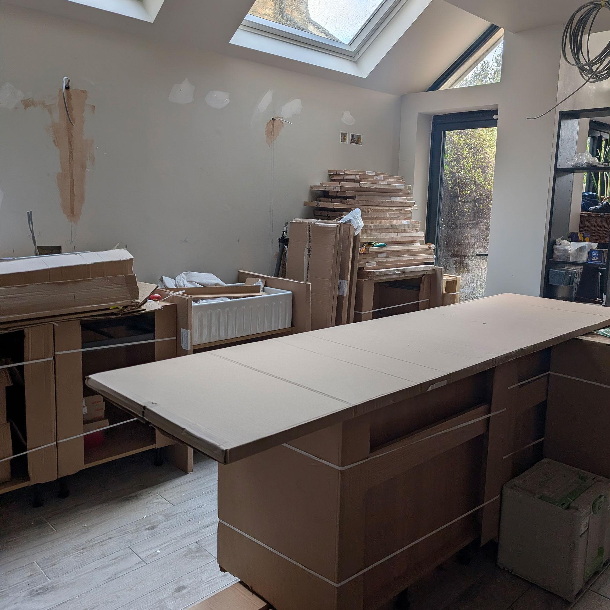 Kitchen mid-renovation with island wrapped up in cardboard
