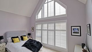Shuttercraft shutters in bedroom on shaped window