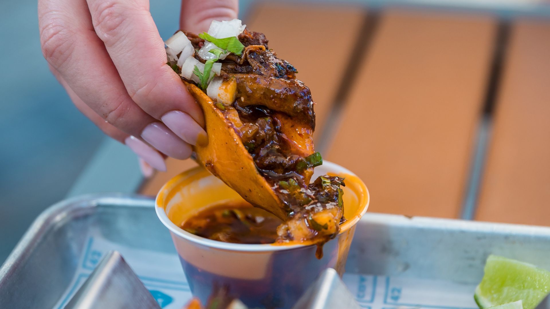 an image of one of Coyp Taco's beef birria tacos being dipping into spicy sauce 