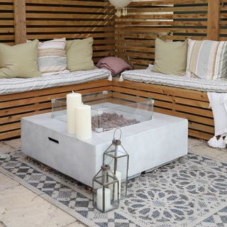 Candles on table in garden and lanterns next to table in front of decking seating area