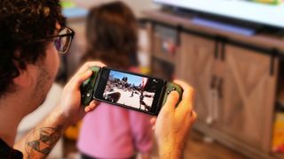 Backbone One Xbox mobile controller in hand with Avowed on screen.