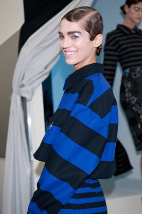Model smiling wearing thick striped clothing and bold make-up
