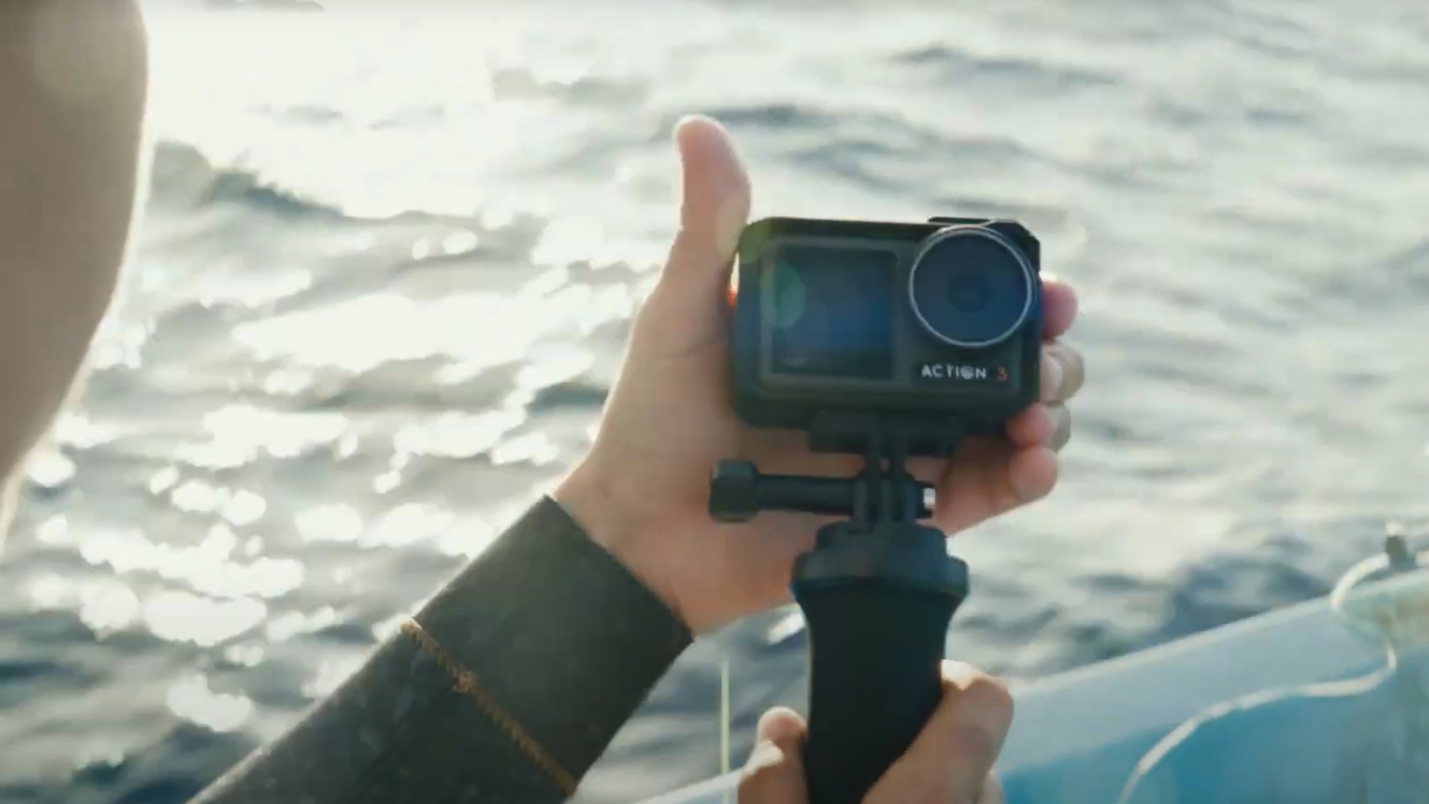 A hand holding the DJI Osmo Action 3 on a stick