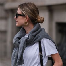 Sophie Pirrung is seen wearing black Nakd pants, a white classic cos shirt, a grey cos sweater, a black leather Celine bag, Celine black sunnies, the row black shoes and aeyde golden earrings on July 27, 2022 in Berlin, Germany