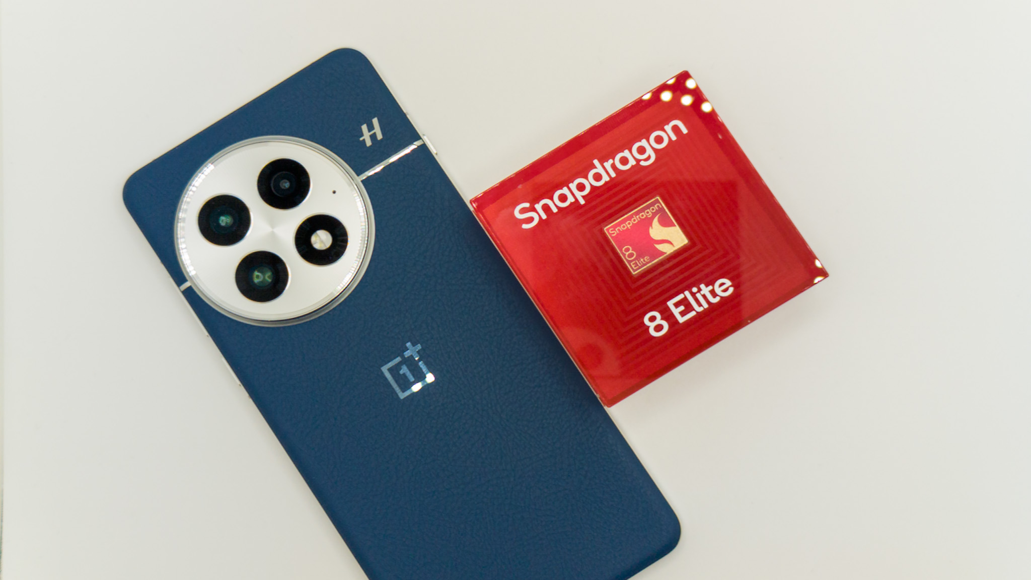 A blue OnePlus 13 with a Snapdragon 8 Elite placard