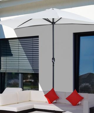 White garden parasol next to a the wall of a house over a patio seating area