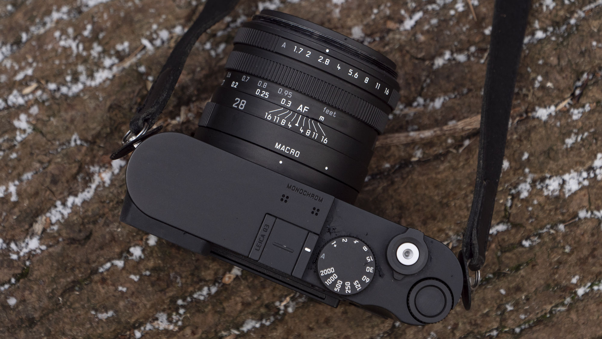 Leica Q3 Monochrom compact camera outside on a snow-dusted log