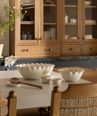 mcgee and co spring 2025 collection kitchen with wooden cabinets island with rattan wood chairs and ceramic wavy bowls