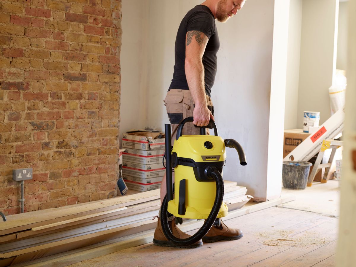 Kärcher WD vacuum being carried through a room covered in dust