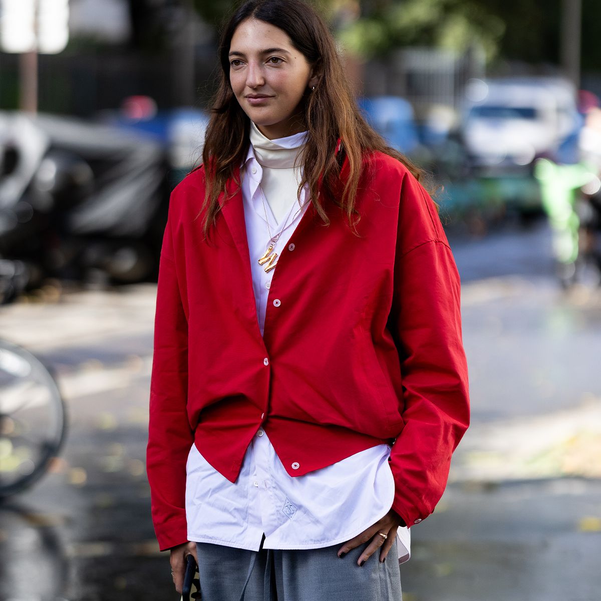 Marta Oldrini wears a red cardigan with grey trousers at Paris Fashion Week 2025.