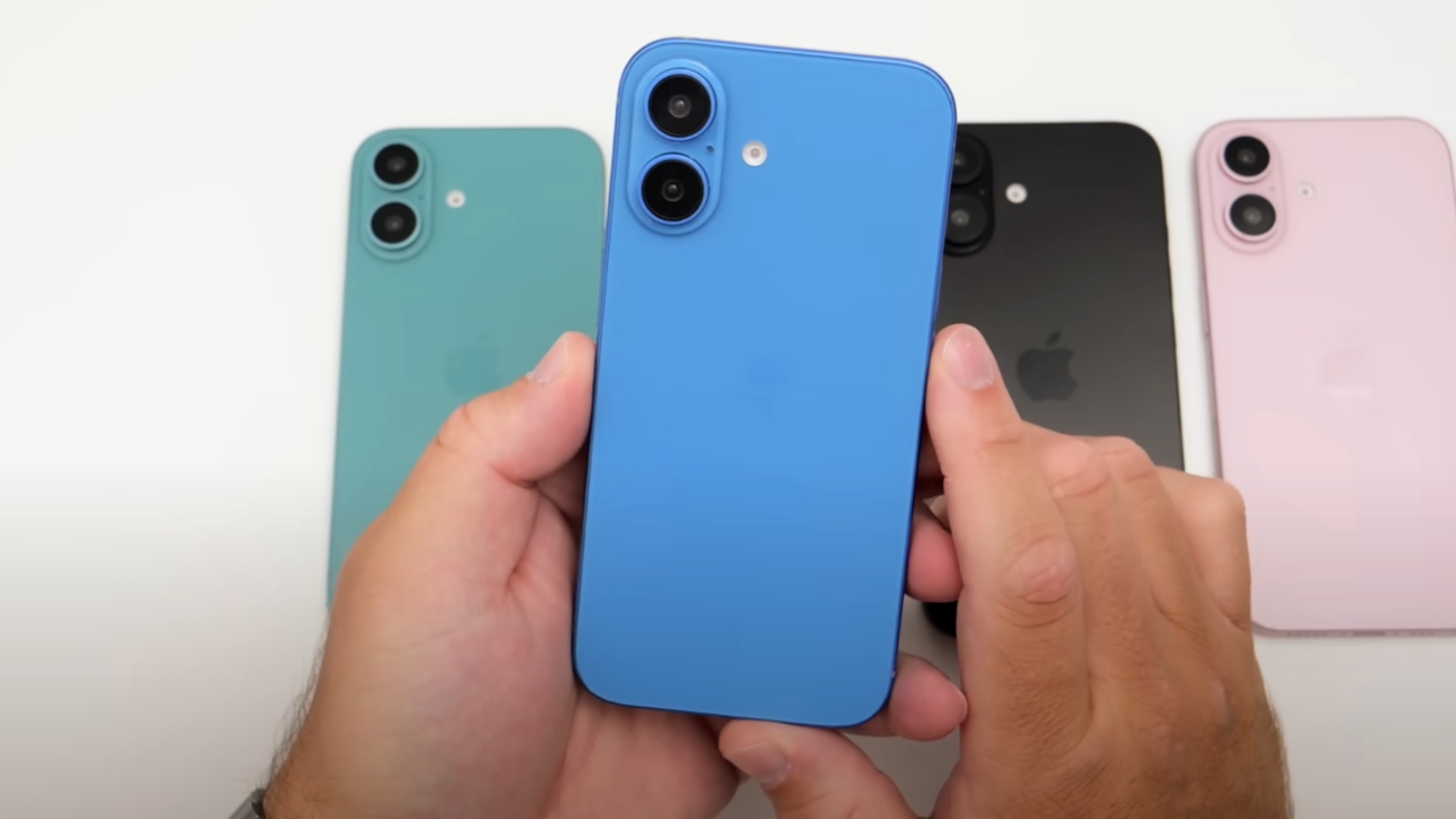 iPhone 16 in hand with multiple colors