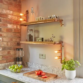 A kitchen with an exposed brick wall and copper lighting fixtures on the wall