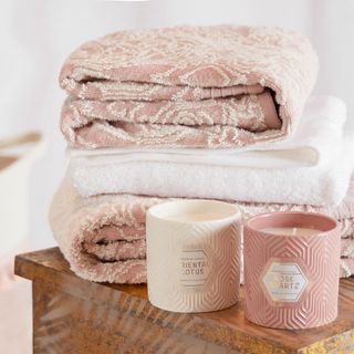 white and pink designed towels and scented candles on wooden table