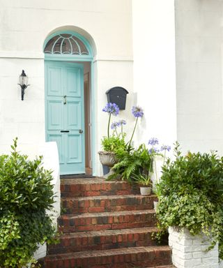 home exterior painted white with light blue front door and brick steps