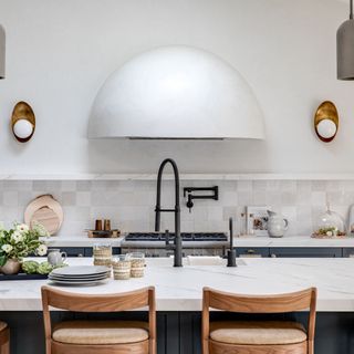White kitchen aesthetic with glazed, textured backsplash tiles, and central island with fresh flowers
