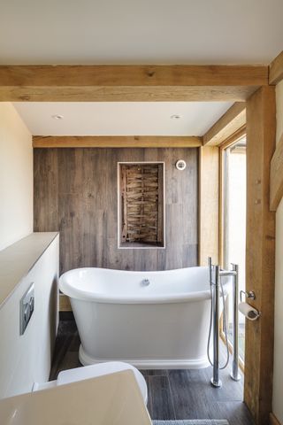 freestanding bath in narrow bathroom with feature panelling on wall
