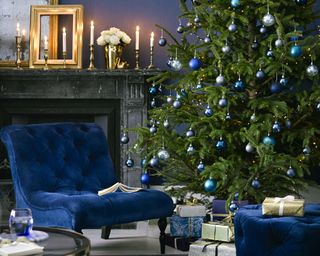 blue themed christmas tree, gifts and fireplace with blue armchair