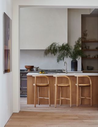 kitchen with wooden island and stools and white walls steel windows