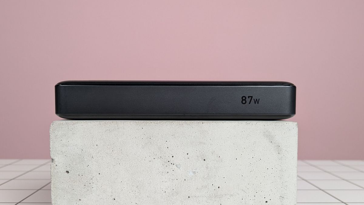 Anker 20,000mAh 87W Power Bank leaning on plinth on desk, with pink background