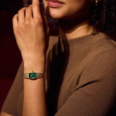 A female model wearing a gold Bulova watch with a green face.