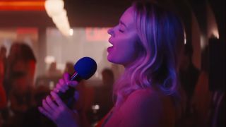 Emily Blunt sings her heart out at karaoke while bathed in purple light in The Fall Guy.