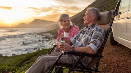 A mature couple on vacation outside their car.