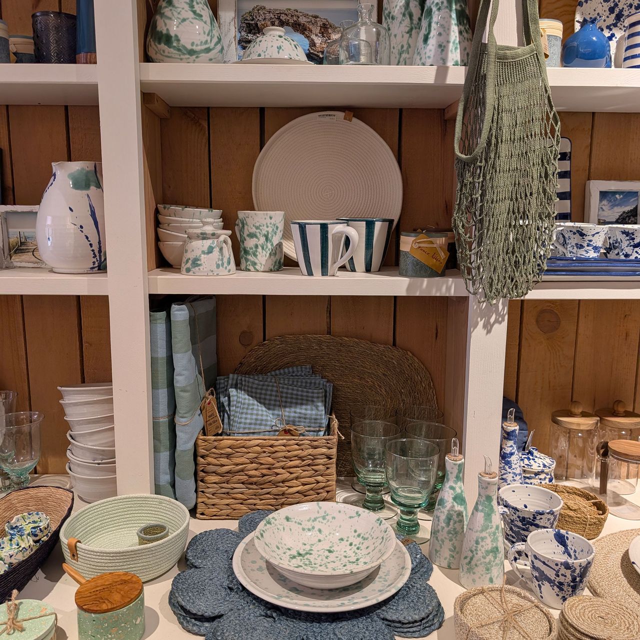 Selection of plates, mugs, glassware and place mats on shop shelves