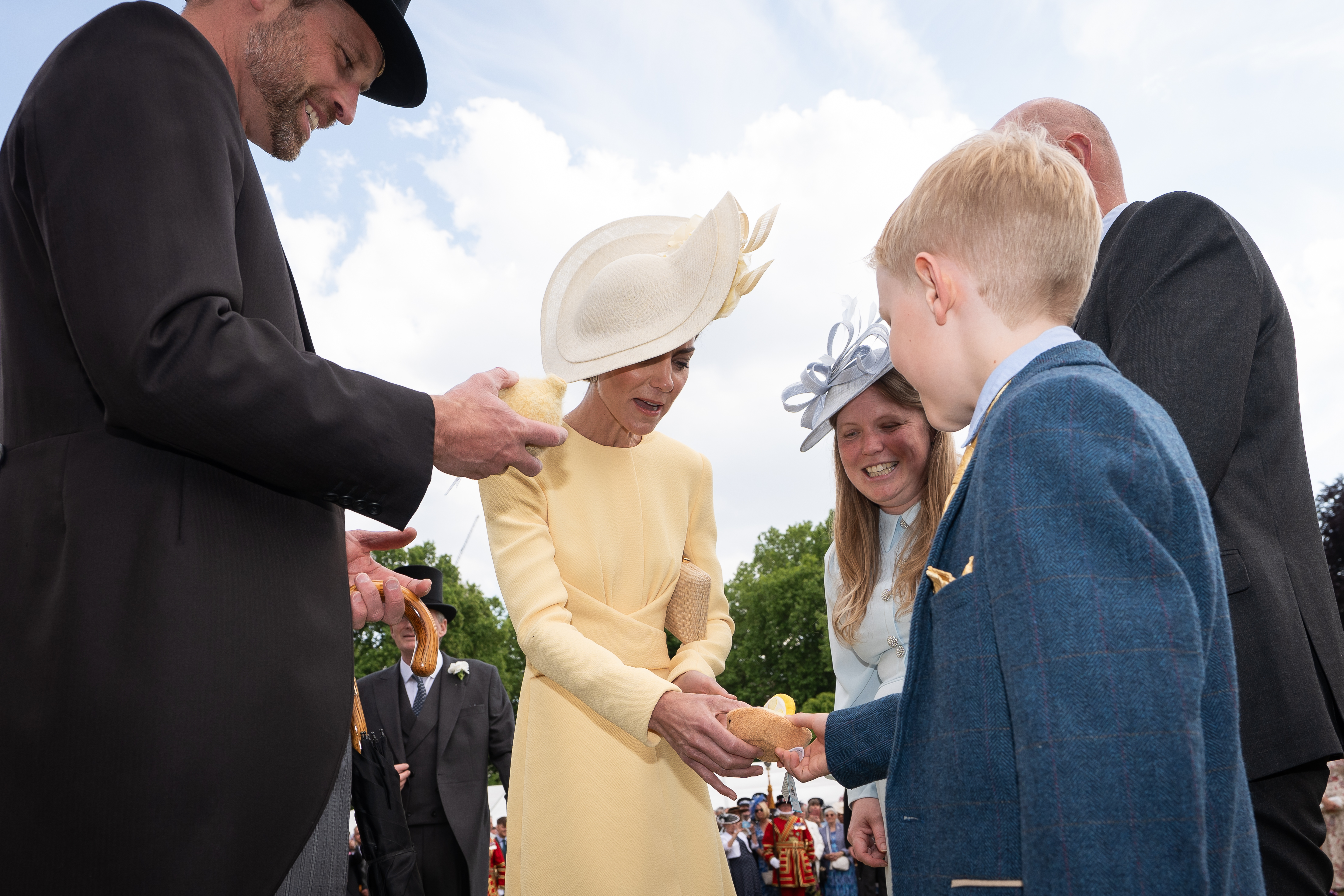 Kate Middleton receiving a stuffed animal from a young boy and Prince William holding his and smiling