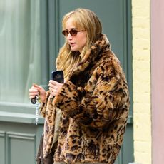Jennifer Lawrence wearing a leopard faux fur coat, tan pants, and bright blue shoes in NYC