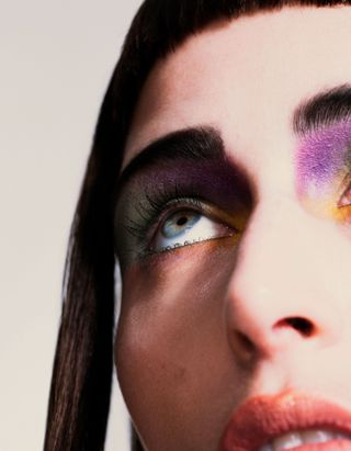 girl with graphic green, purple, and yellow eyeshadow and glossy pink lips