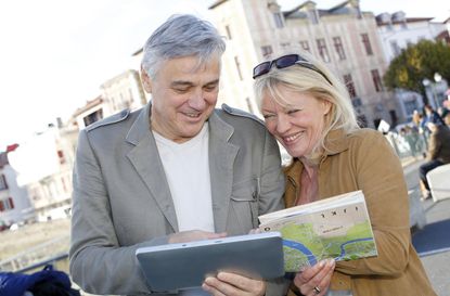 Senior couple visiting old city with map and tablet