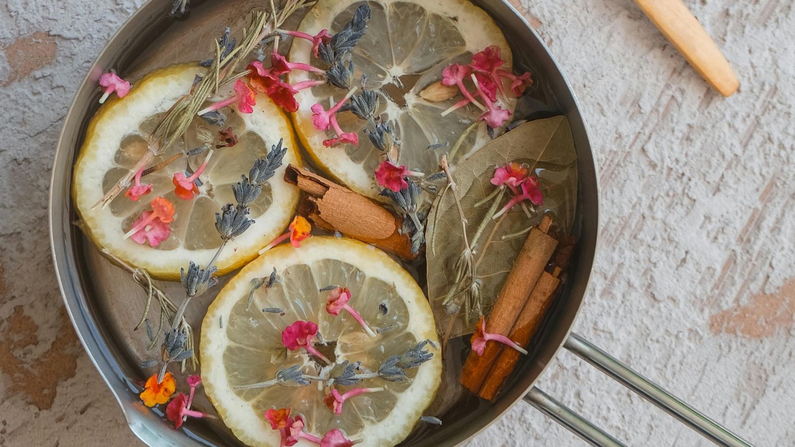 Aerial view of metal simmer pot filled with sliced lemons, dried flowers and cinnamon sticks