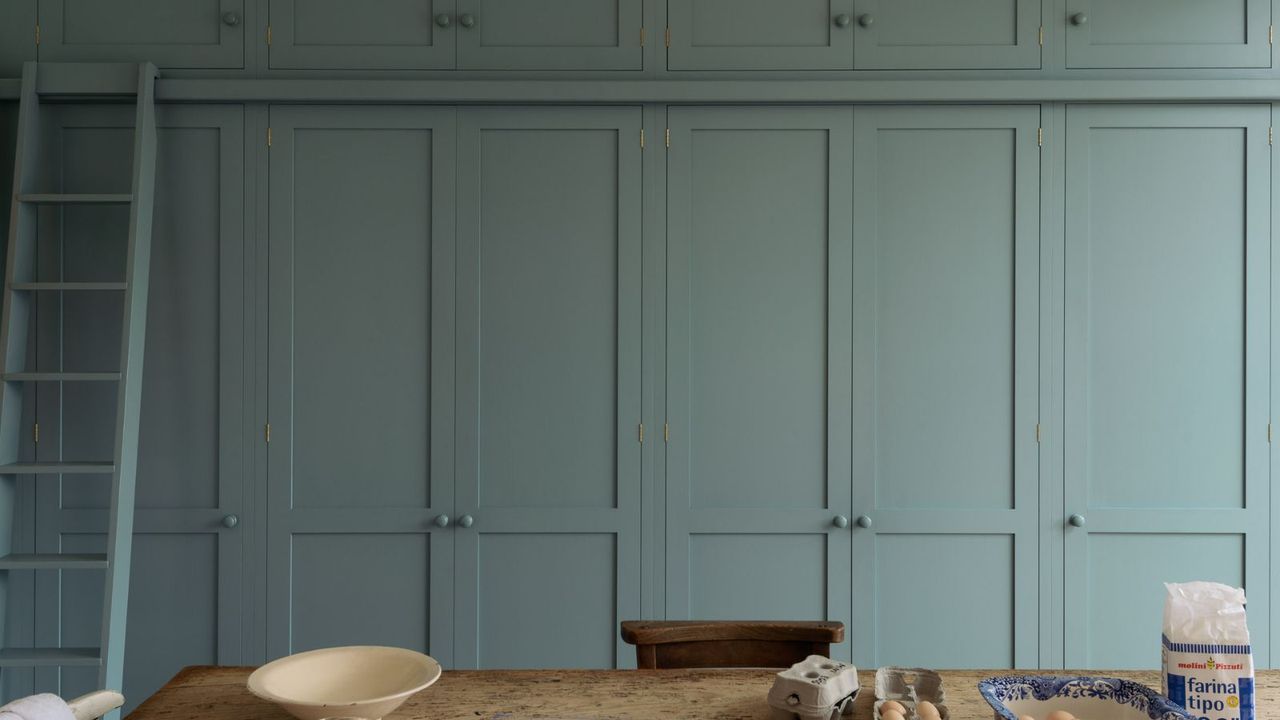 Teal blue floor to ceiling built-in cabinets with a kitchen ladder to reach top doors