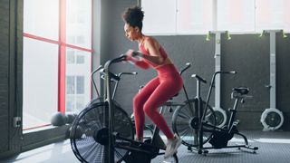Woman using assault bike in gym