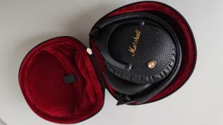 A pair of Marshall Monitor III A.N.C headphones folded up inside their clam shell carry case. The interior of the case is made from red velvet.